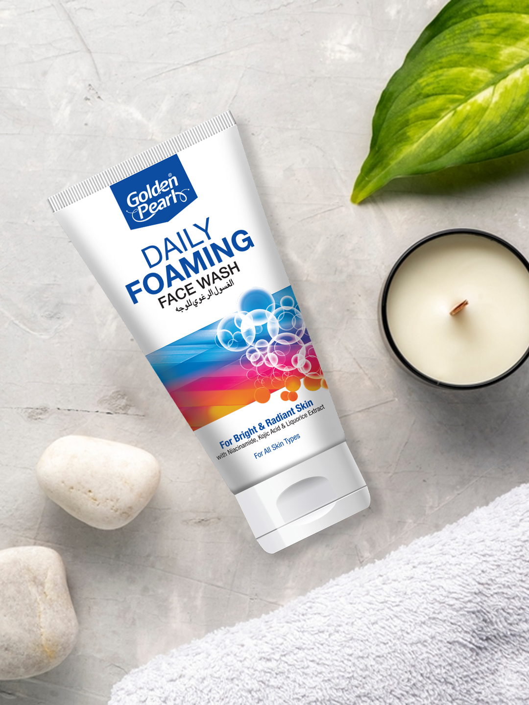 Tube of Golden Pearls Daily Foaming Face Wash on a light surface with a candle and leaves.