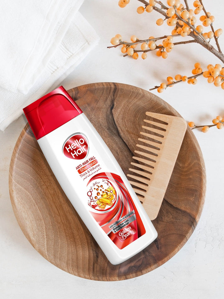 Hello Hair shampoo bottle with a wooden comb on a wooden plate, with decorative elements in the background.